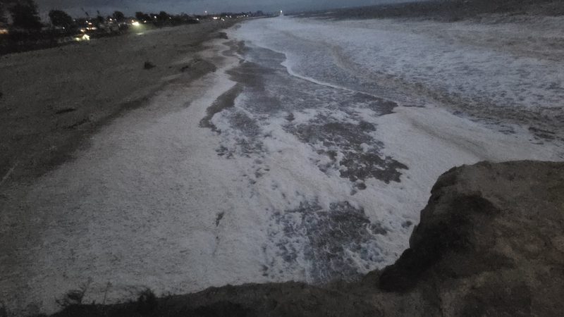 Sea foam blankets the dusk shore