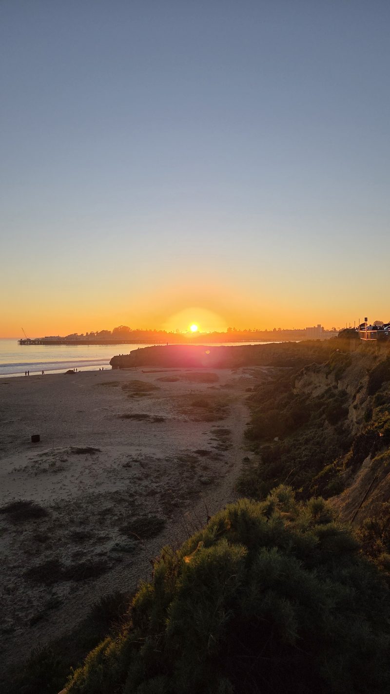 Sun sinking behind the distant pier